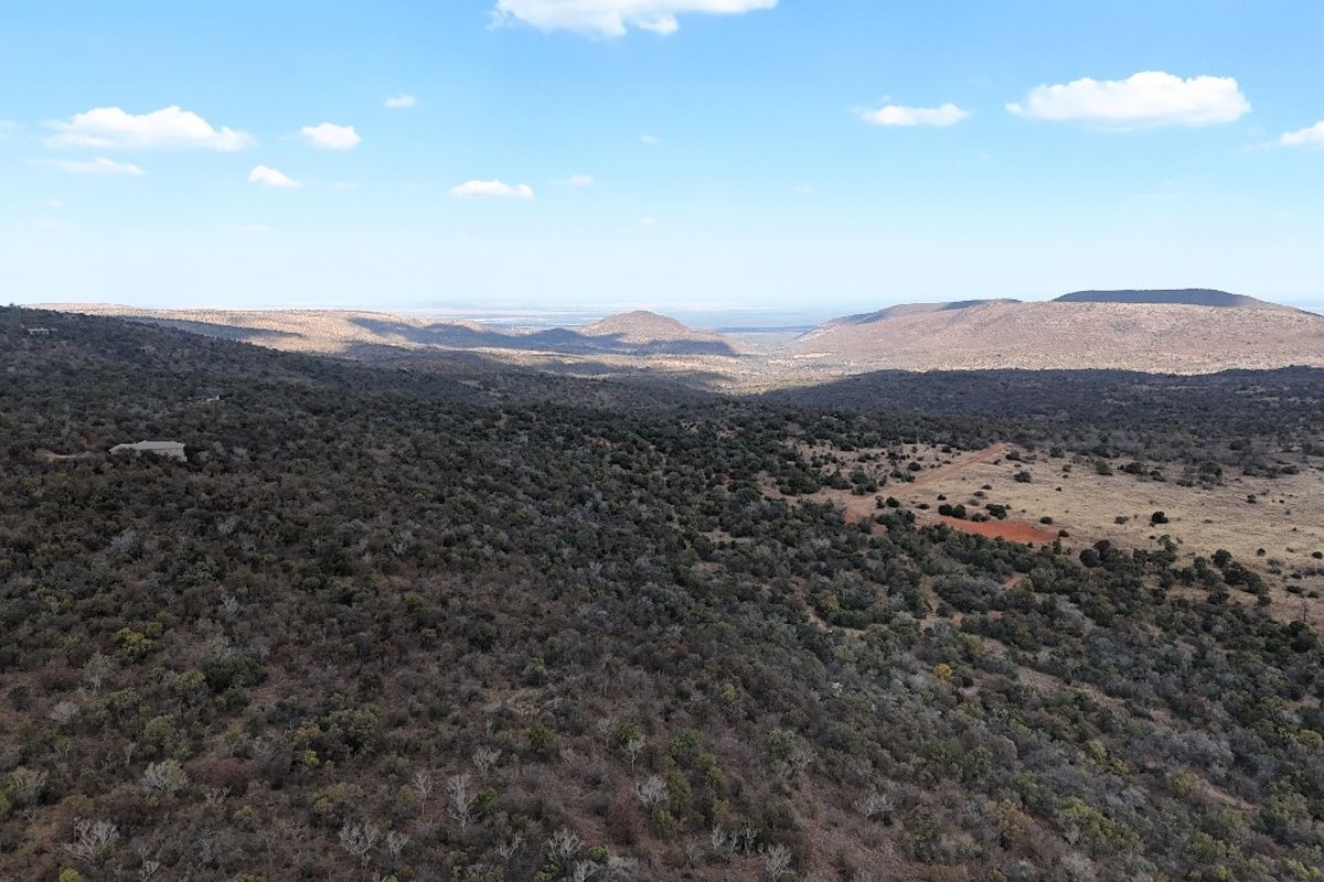 An expansive aerial view of the natural landscape, showcasing the vast terrain and surrounding hills of the vacant residential property.