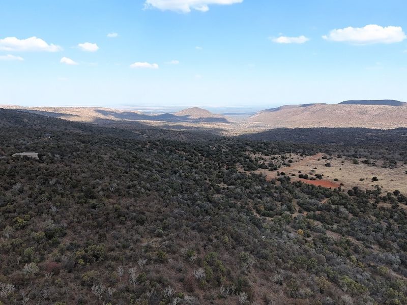 An expansive aerial view of the natural landscape, showcasing the vast terrain and surrounding hills of the vacant residential property.