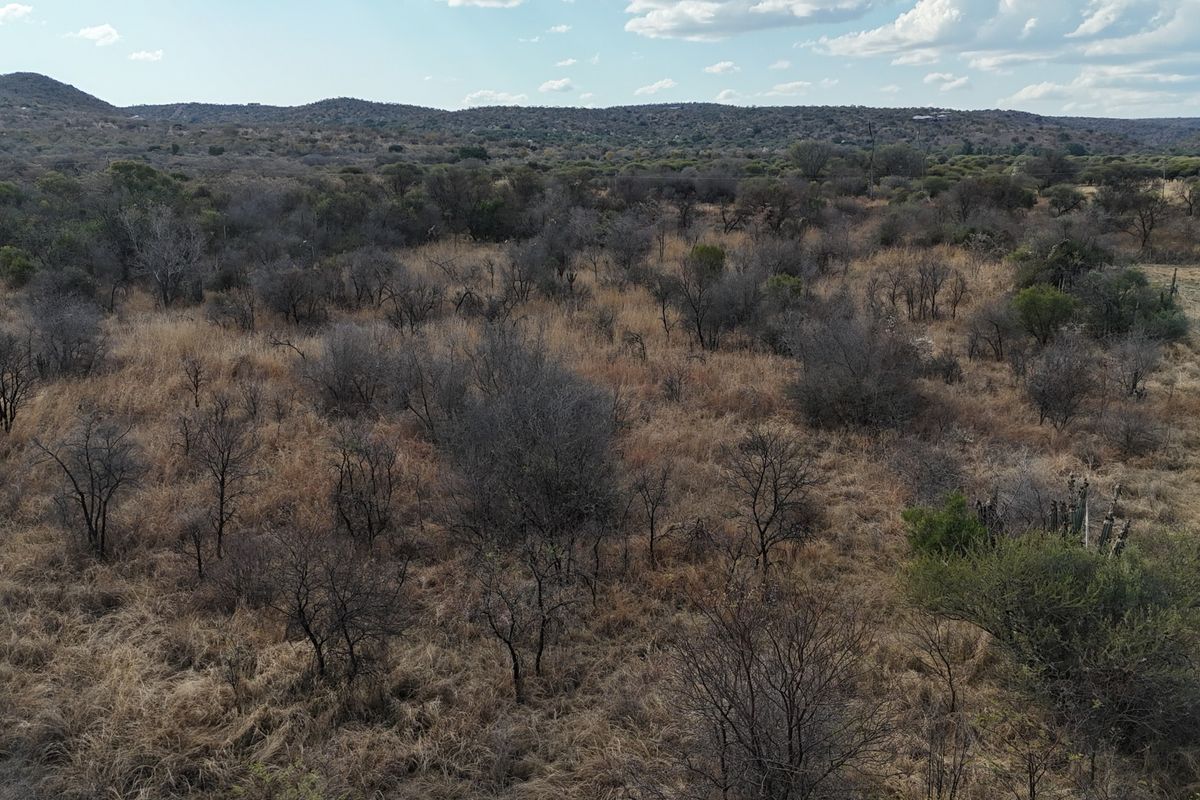 An aerial view of a large, undeveloped residential land plot featuring natural bushveld vegetation and distant hilly terrain.