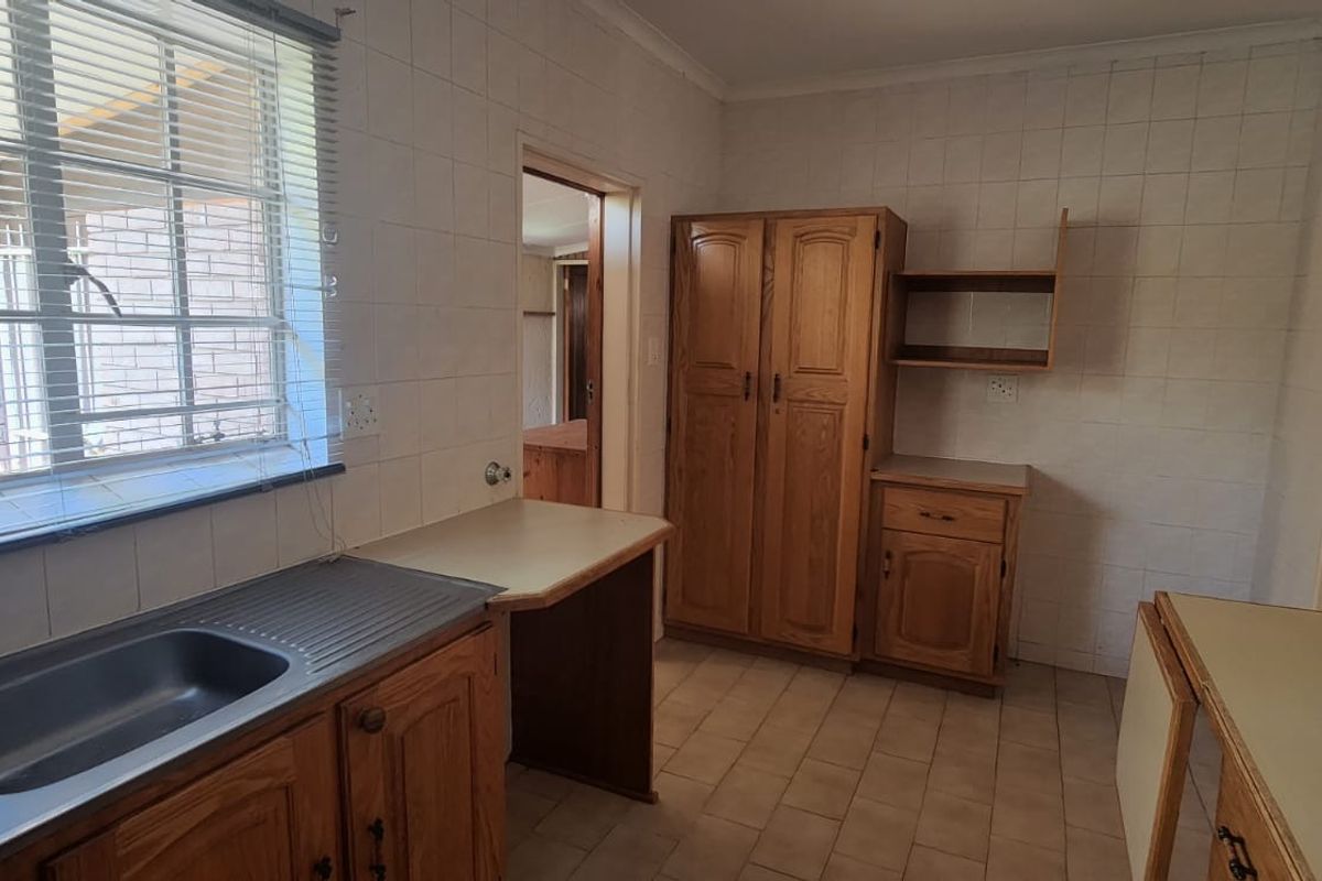 A functional kitchen space featuring built-in wooden cabinetry, laminate countertops, and a double bowl stainless steel sink, ready for modernization.
