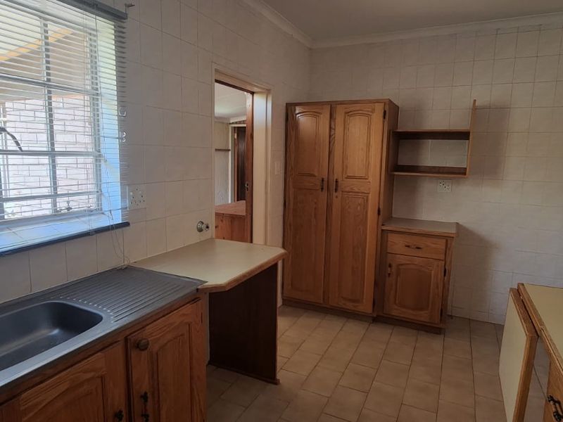 A functional kitchen space featuring built-in wooden cabinetry, laminate countertops, and a double bowl stainless steel sink, ready for modernization.