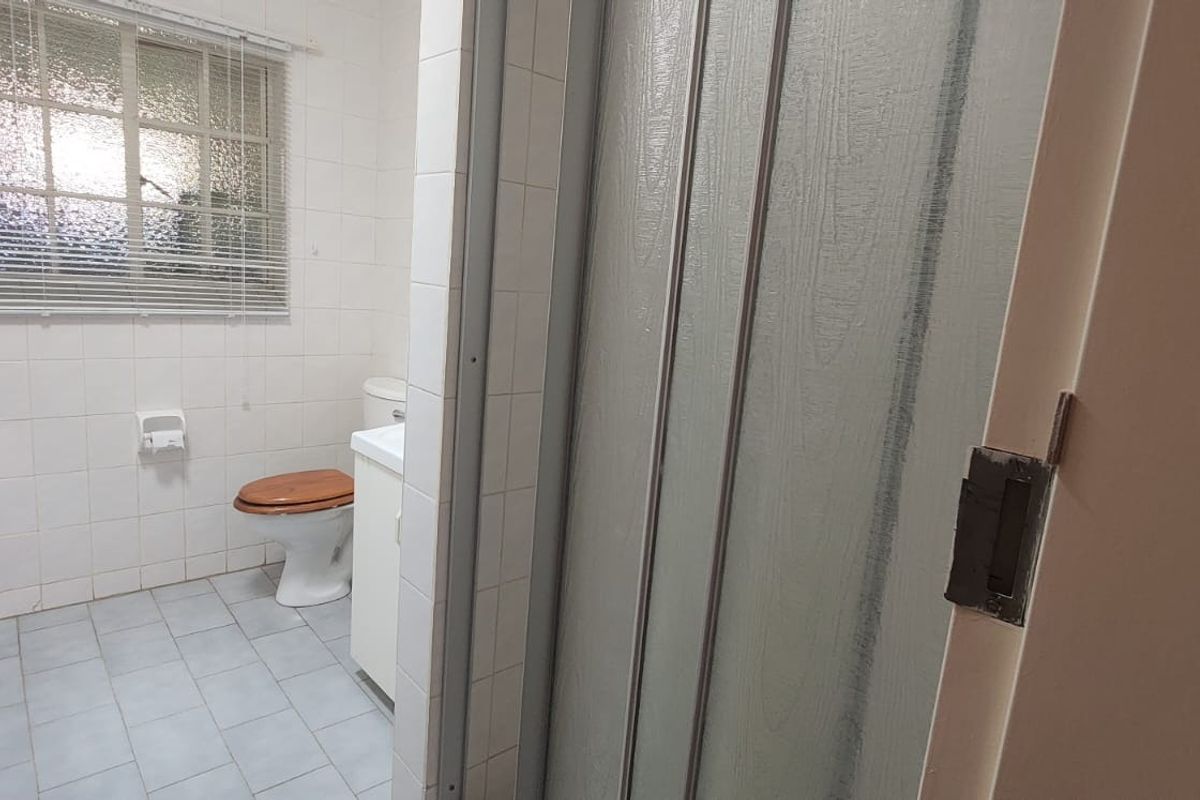 A functional bathroom featuring tiled walls and floors, a vanity cabinet, a toilet, and a shower enclosure with a sliding door.