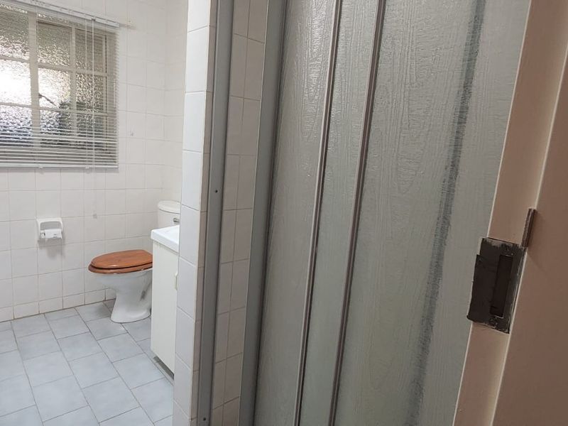 A functional bathroom featuring tiled walls and floors, a vanity cabinet, a toilet, and a shower enclosure with a sliding door.