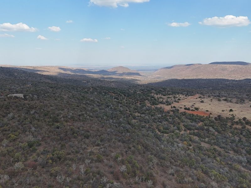 An aerial view of the expansive, undeveloped residential land featuring natural bushveld terrain and scenic mountain vistas.
