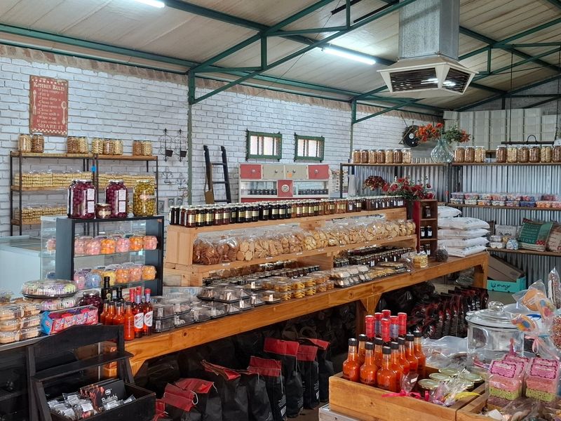 A spacious farm-style retail or utility area featuring exposed steel roof trusses, painted brick walls, and industrial-grade lighting and ventilation systems.