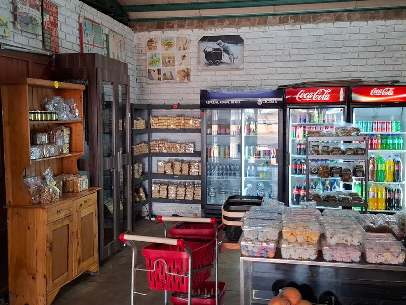 A commercial retail space featuring exposed brick walls, industrial shelving, and multiple commercial refrigeration units for food and beverage display.