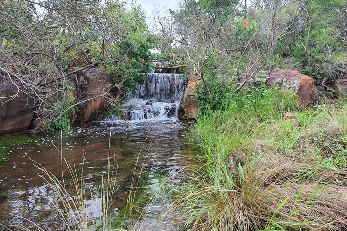 A scenic view of a natural waterfall cascading over rock formations within the property's landscape.