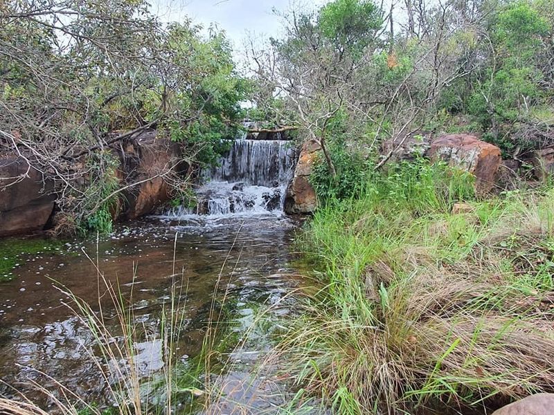 A scenic view of a natural waterfall cascading over rock formations within the property's landscape.