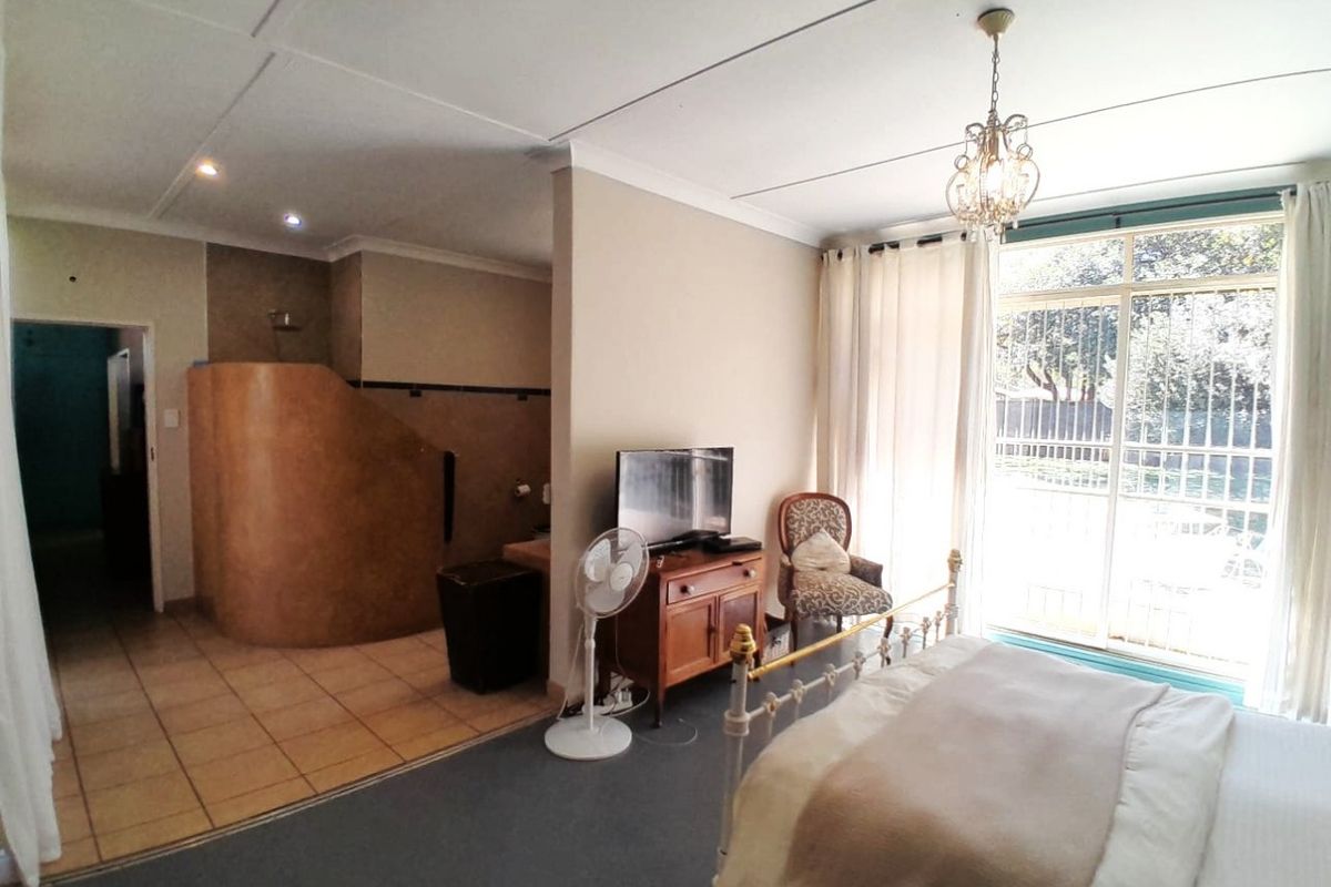 Spacious bedroom featuring an open-plan en-suite bathroom, tiled flooring, and large sliding doors providing access to the exterior.
