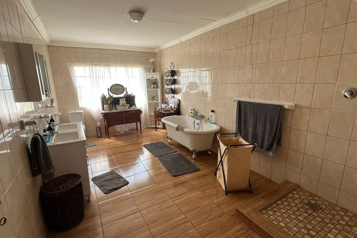 Spacious bathroom featuring a classic clawfoot bathtub, double vanity, and a walk-in shower with tiled finishes throughout.