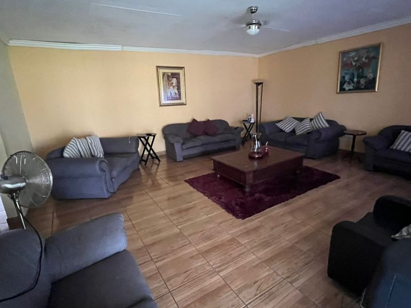 Spacious living room featuring tiled flooring, coved ceilings, and a central ceiling fan, offering a comfortable and functional layout.