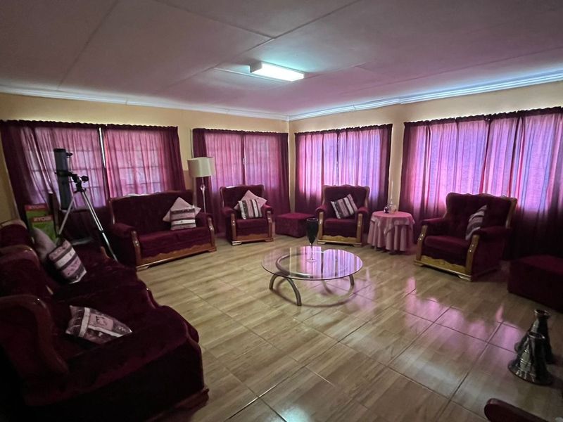 Spacious living room featuring tiled flooring and multiple windows with curtains, providing a bright and functional area for relaxation.