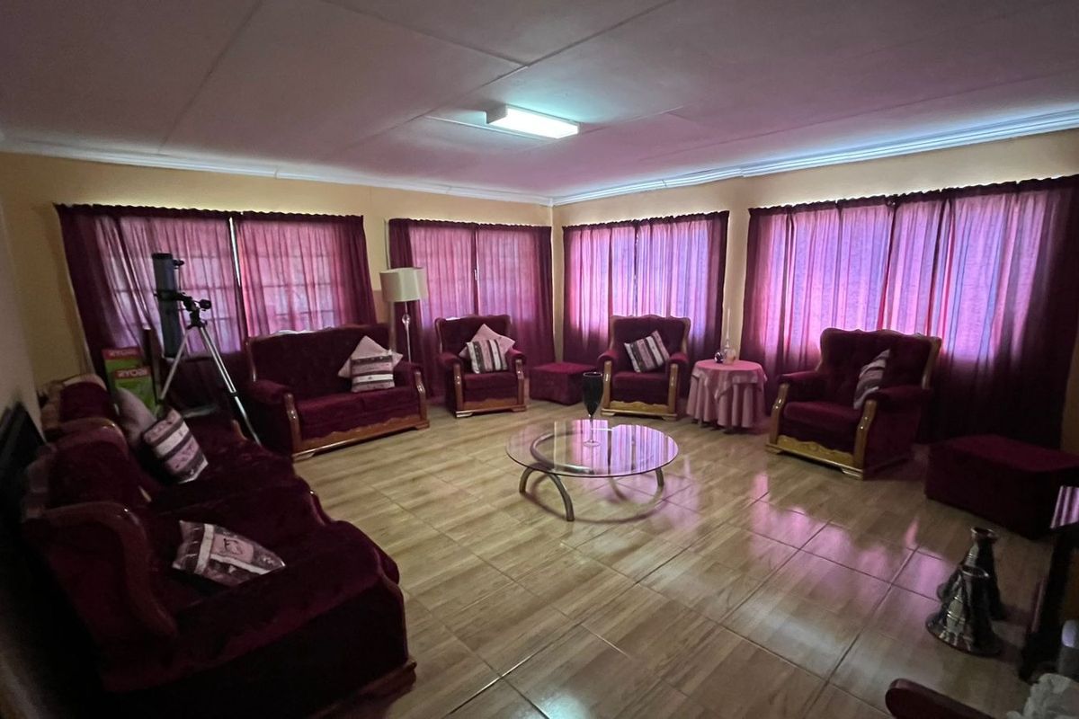 Spacious living room featuring tiled flooring and multiple windows with curtains, providing a bright and functional area for relaxation.