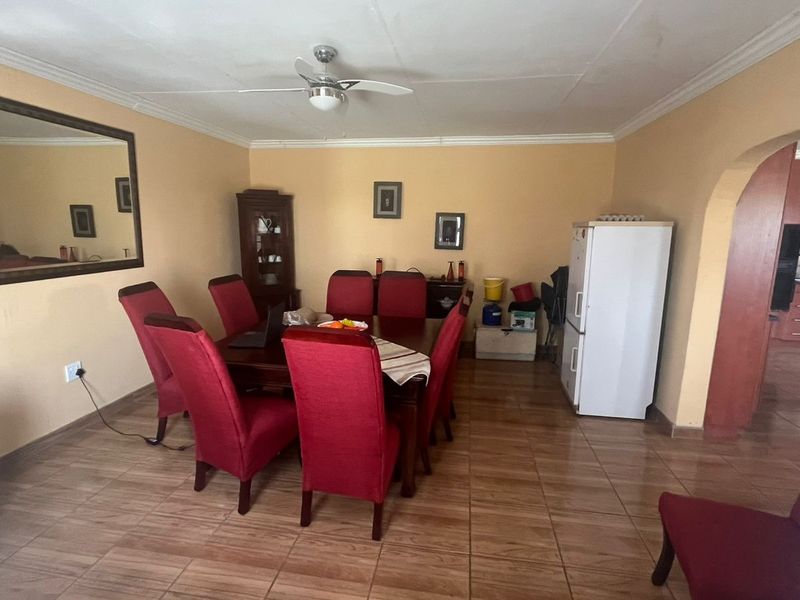 Dining room featuring tiled flooring, a ceiling fan, and an arched entryway leading to the kitchen area.