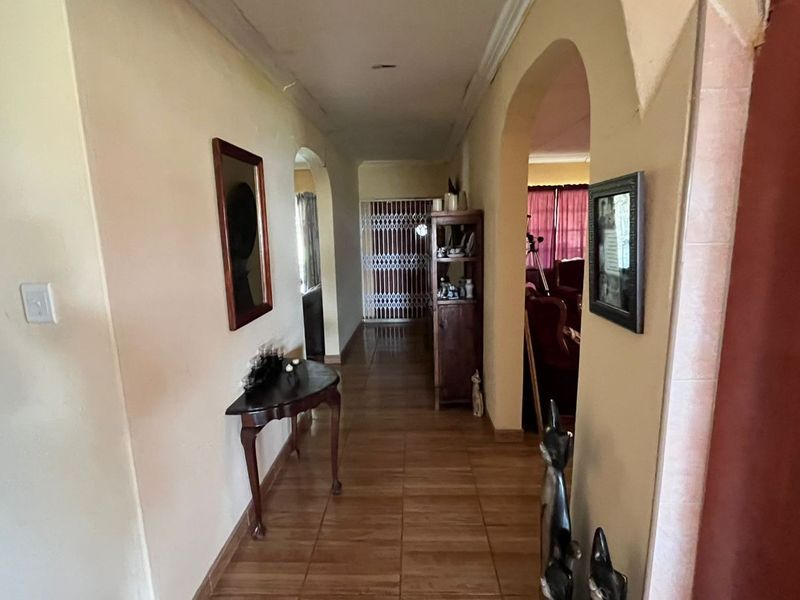 A central hallway featuring tiled flooring and arched transitions leading to adjacent living spaces, showing signs of wear on the ceiling.