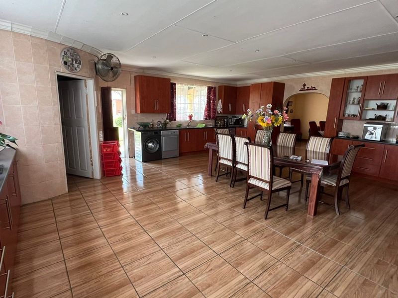 Spacious open-plan kitchen and dining area featuring wood-finish cabinetry, tiled flooring, and direct access to adjacent living spaces.
