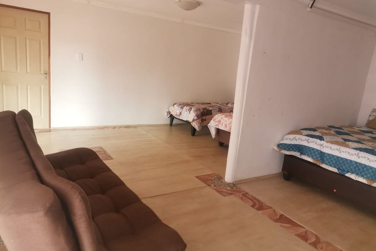A spacious bedroom area featuring tiled flooring with decorative accents, coving, and a neutral wall finish.