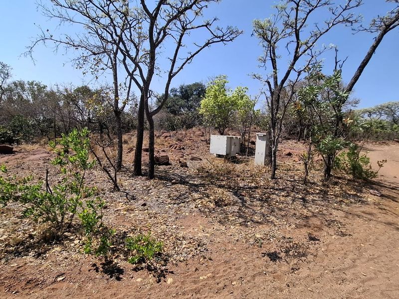 A view of the vacant residential land featuring natural vegetation, rocky terrain, and an existing electrical utility connection point.