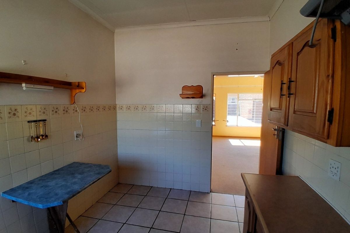 A dated kitchen featuring tiled walls and flooring with wooden cabinetry, offering a blank canvas for renovation and modernization.