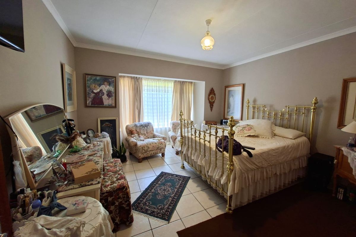 A spacious bedroom featuring tiled flooring, coved ceilings, and a large window allowing natural light, offering a comfortable and functional living space.
