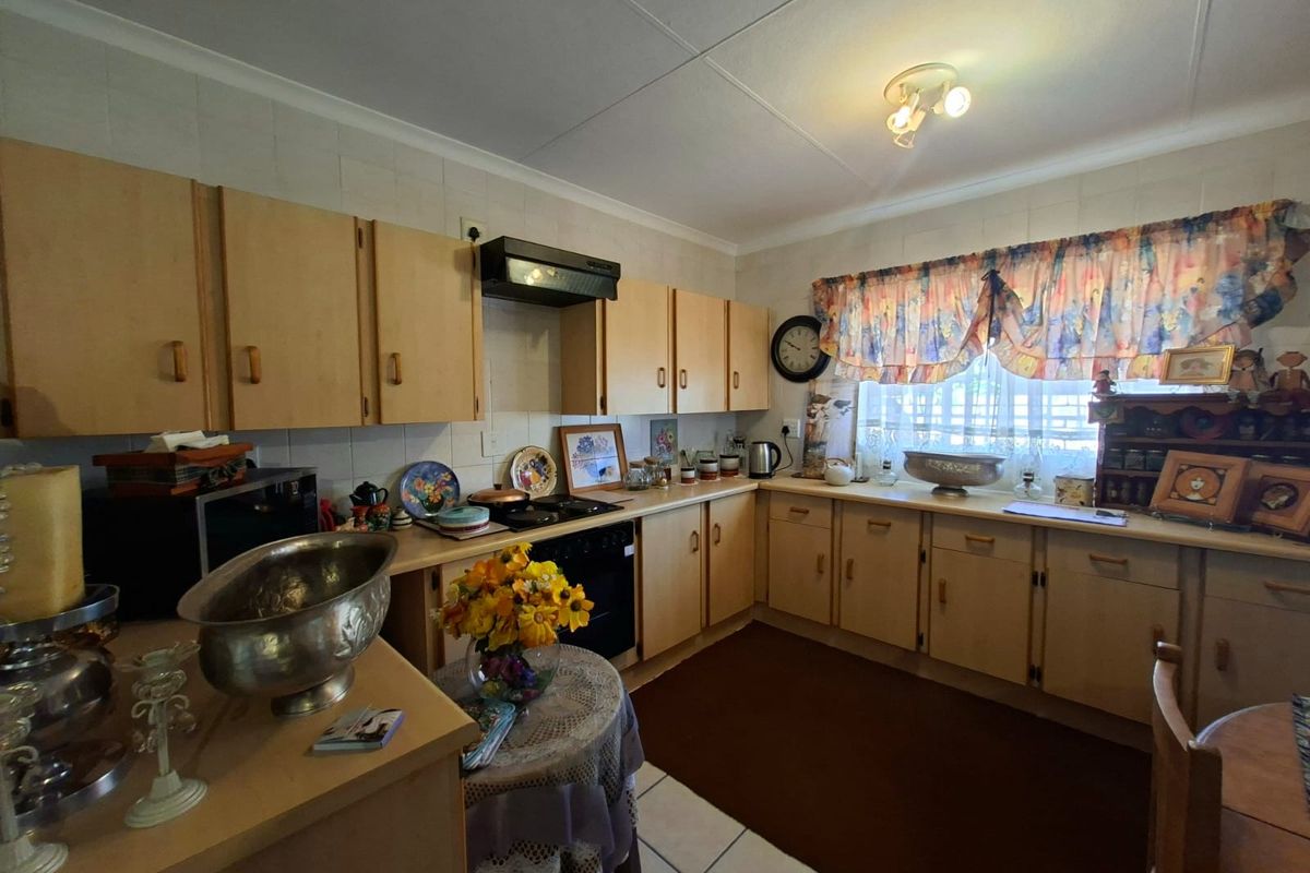 A functional kitchen featuring laminate cabinetry, built-in oven, hob, and extractor fan with tiled flooring and backsplash.