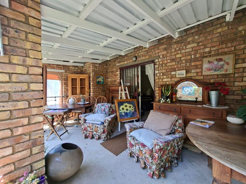 A covered patio area featuring exposed brick walls, concrete flooring, and a corrugated metal roof, providing a rustic outdoor living space.