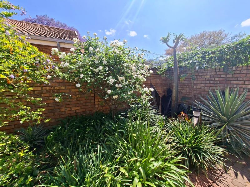 A well-established private garden area featuring mature landscaping, lush greenery, and a sturdy brick boundary wall.