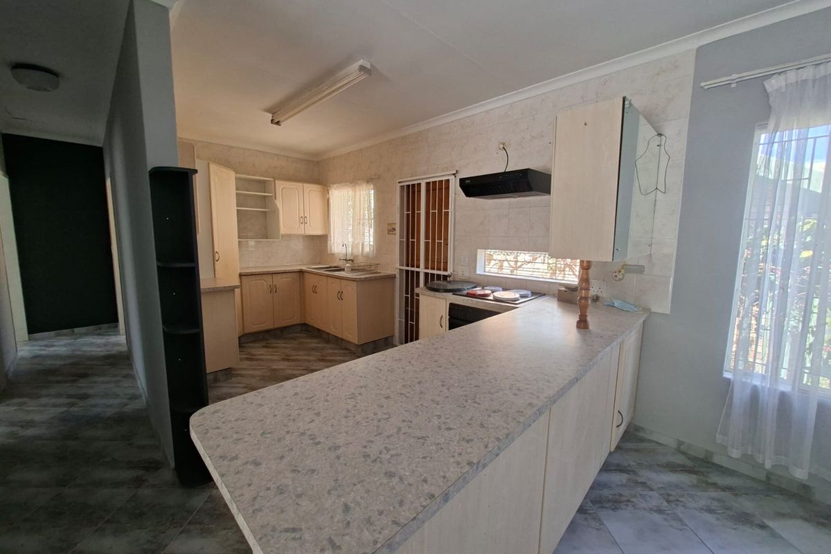 Functional kitchen featuring laminate cabinetry, built-in oven with extractor fan, and a breakfast bar counter, offering a practical layout for daily meal preparation.