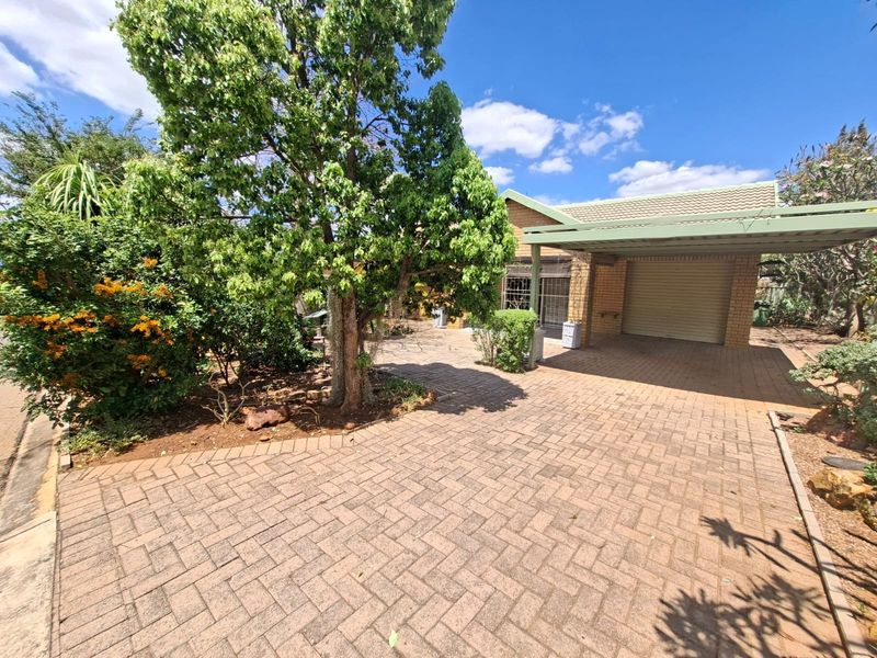 Front exterior view of the property featuring a paved driveway, a covered carport, and a face brick facade with a tiled roof.