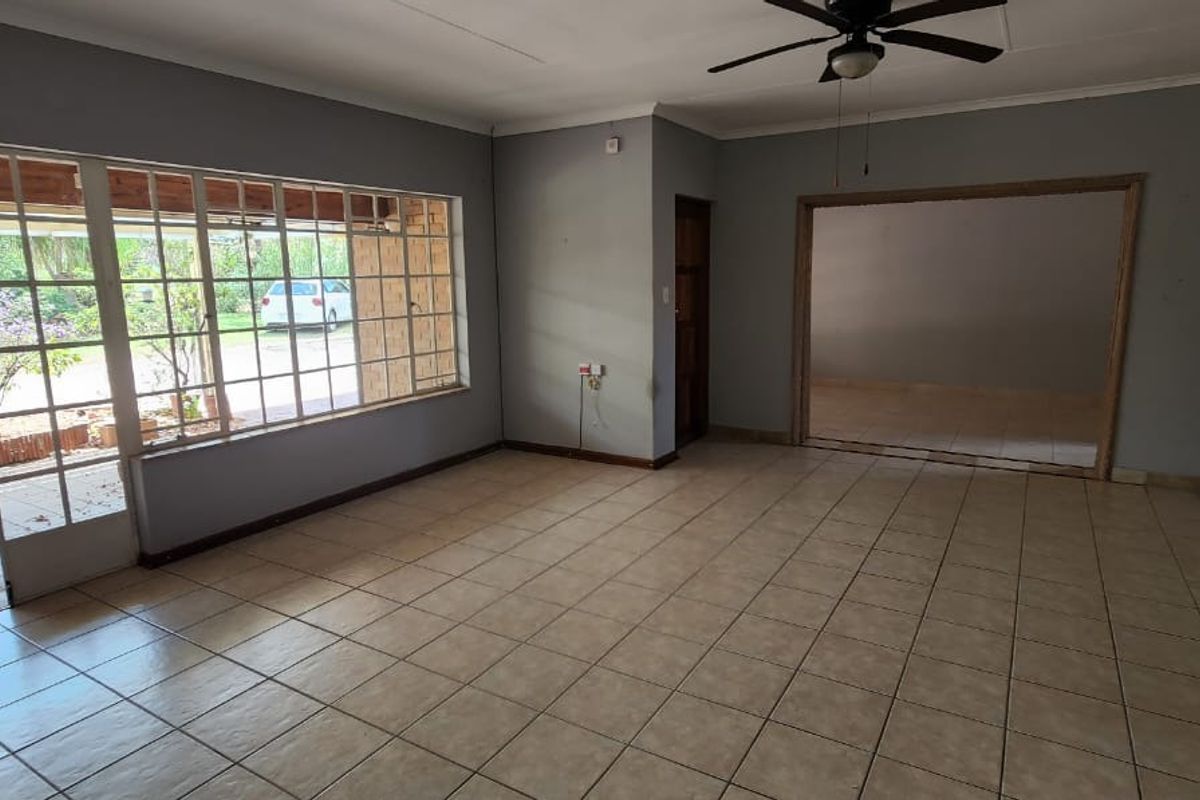 Spacious, empty living room featuring tiled flooring, a ceiling fan, and large glass sliding doors providing access to the outdoor patio area.