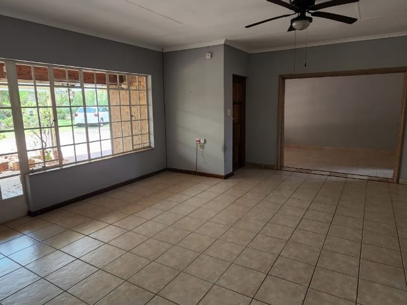 Spacious, empty living room featuring tiled flooring, a ceiling fan, and large glass sliding doors providing access to the outdoor patio area.