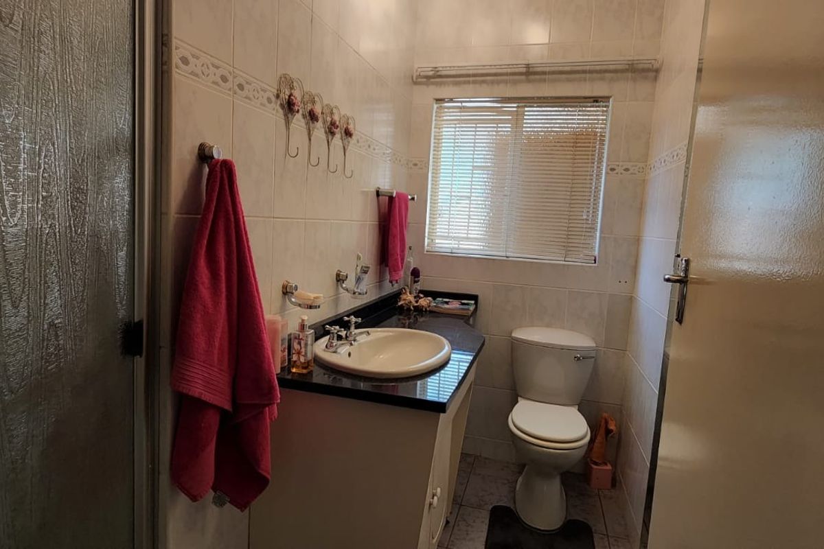 A functional bathroom featuring a shower enclosure, vanity basin with granite countertop, and tiled finishes throughout.
