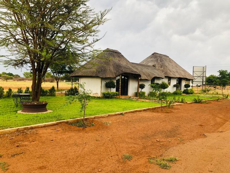 A charming small holding property featuring a traditional thatch-roofed dwelling set within a spacious, well-maintained garden area.