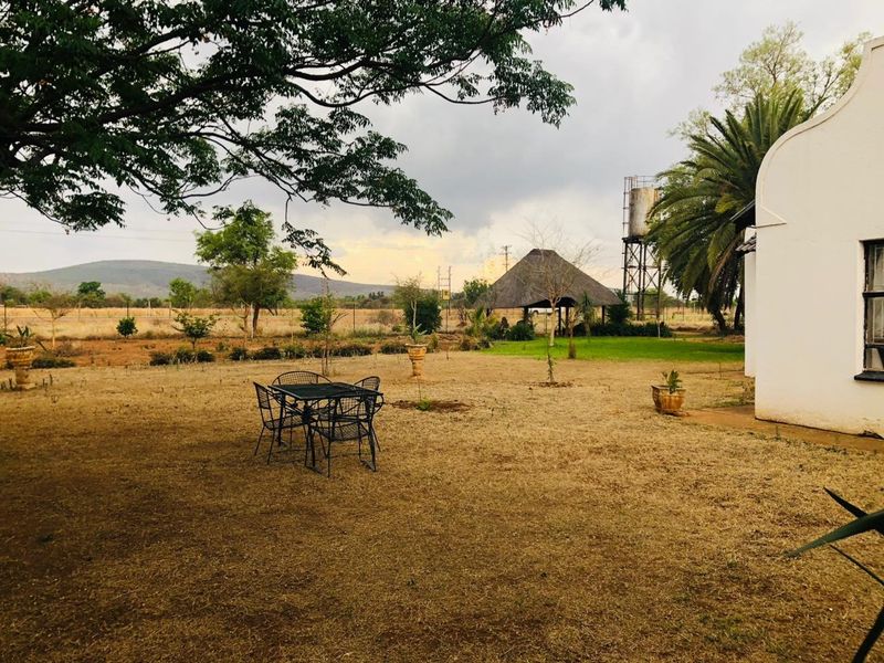 Spacious garden area featuring a water tank, a thatched lapa structure, and expansive views of the surrounding landscape.