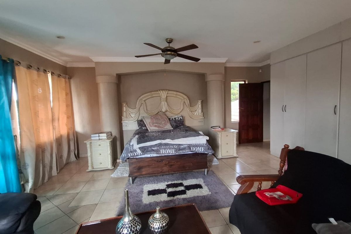 Spacious bedroom featuring tiled flooring, built-in cupboards, and a central ceiling fan, offering a functional layout with neutral wall tones.