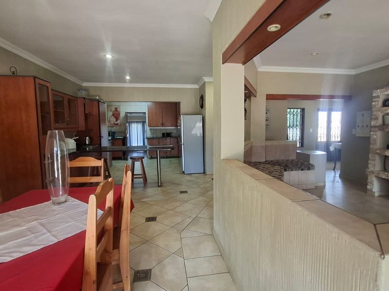 Spacious open-plan living and kitchen area featuring tiled floors, built-in cabinetry, and a distinctive stone-clad fireplace, offering a functional and connected layout.