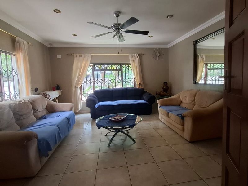 Spacious living room featuring tiled flooring, recessed lighting, a ceiling fan, and security bars on the windows.