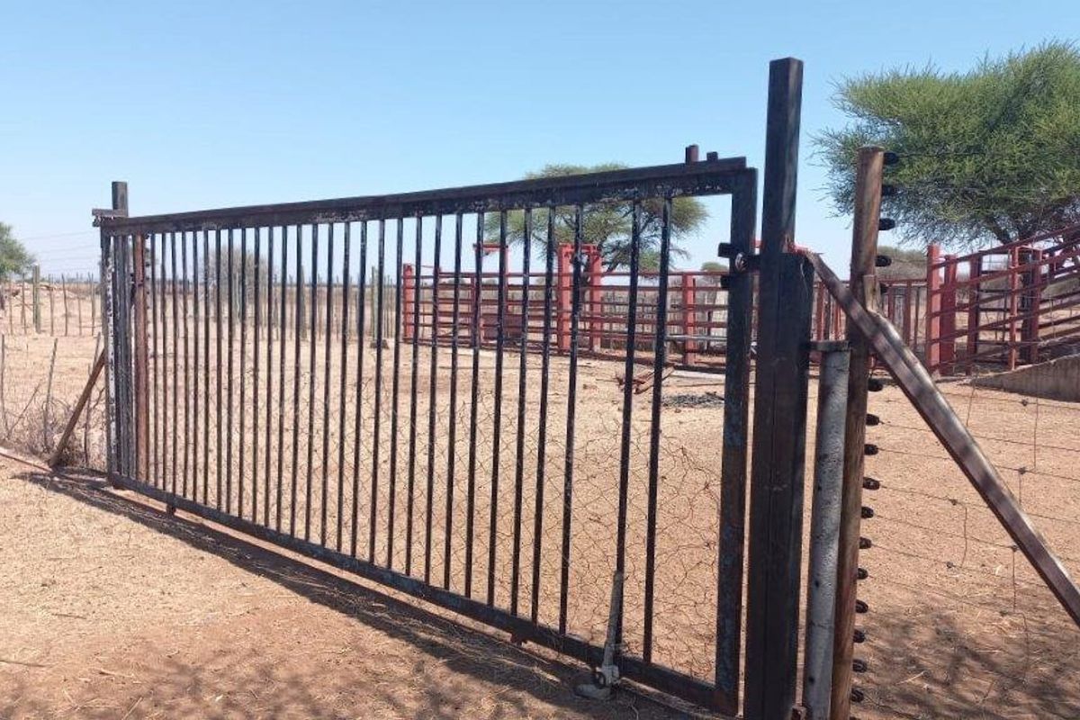 A functional farm gate and electric fencing securing the cattle handling pens and livestock management area on the property.