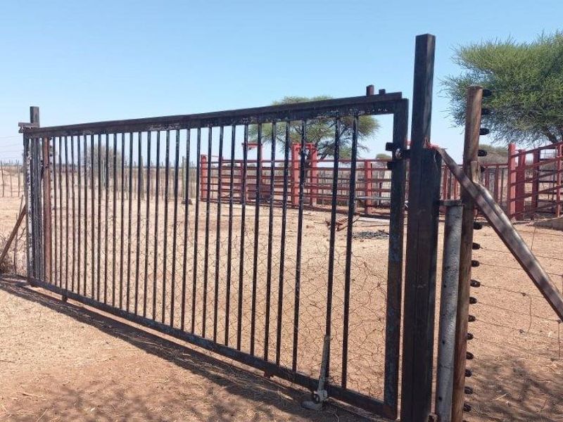 A functional farm gate and electric fencing securing the cattle handling pens and livestock management area on the property.