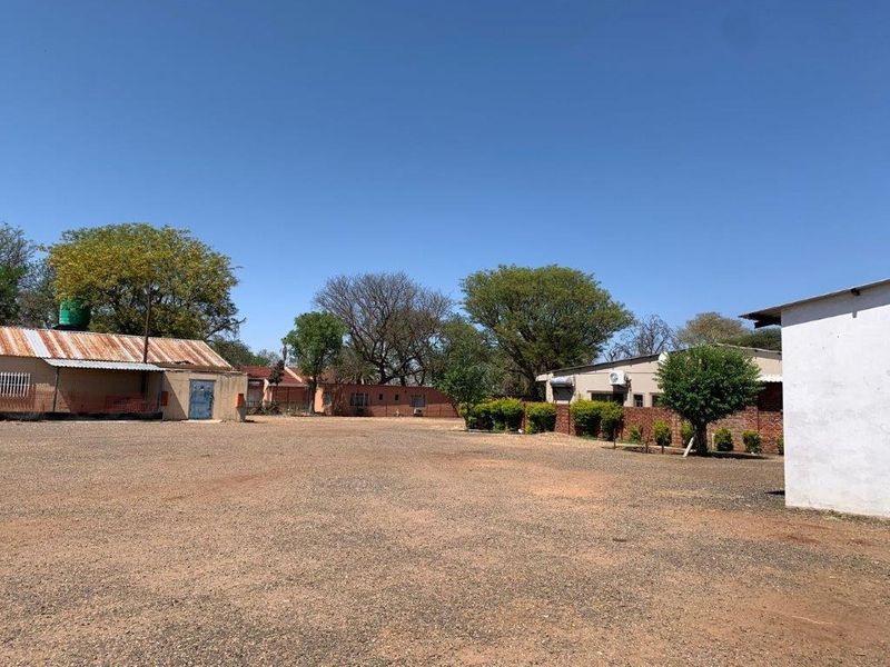 A wide view of the farm yard featuring multiple outbuildings with corrugated metal roofing and gravel ground cover.