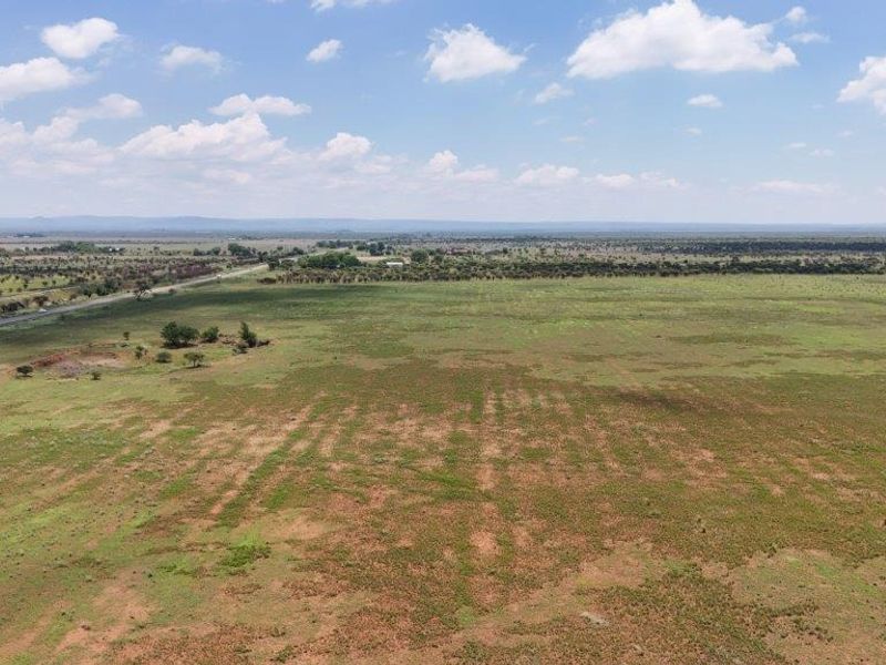 An aerial view of expansive open farm land with visible road access and surrounding rural landscape.