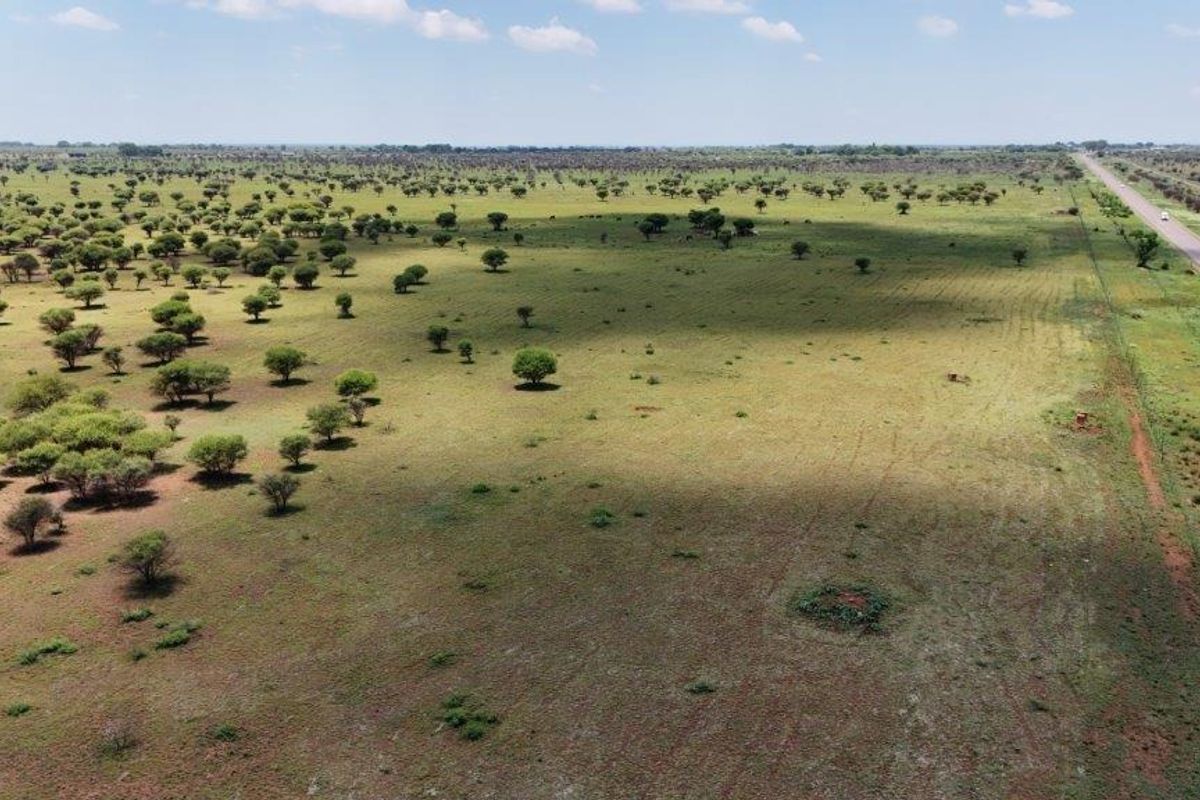An aerial view of expansive farm land featuring natural vegetation and direct road access.