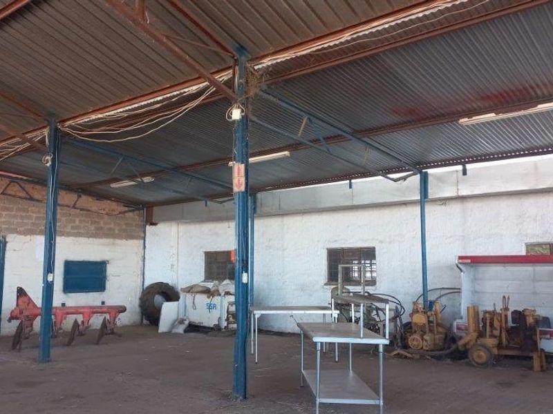A large, open-plan utility or storage shed featuring a corrugated metal roof, steel support structure, and concrete block walls.