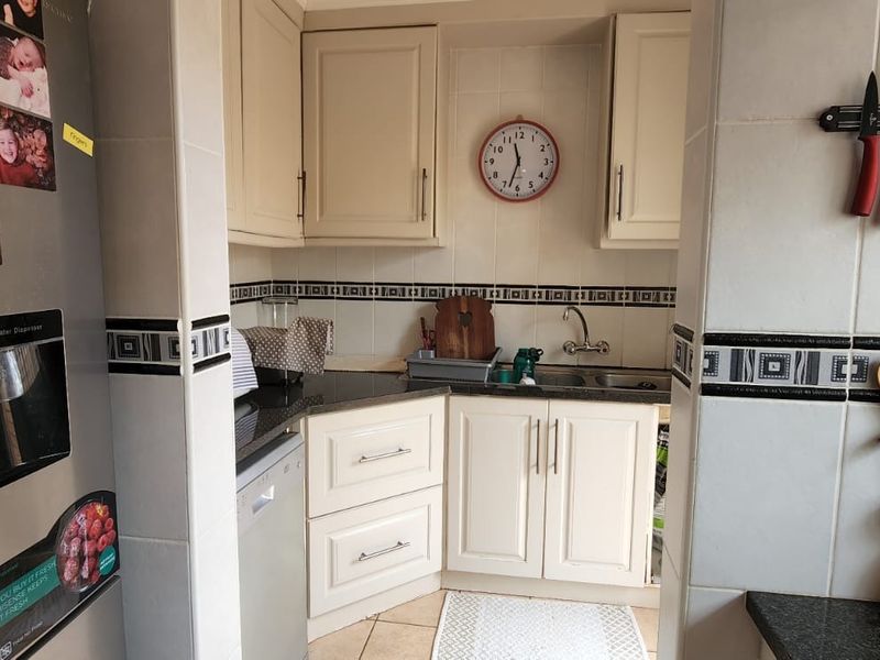 A functional kitchen area featuring cream-colored cabinetry, granite countertops, a double sink, and decorative tiled backsplash.