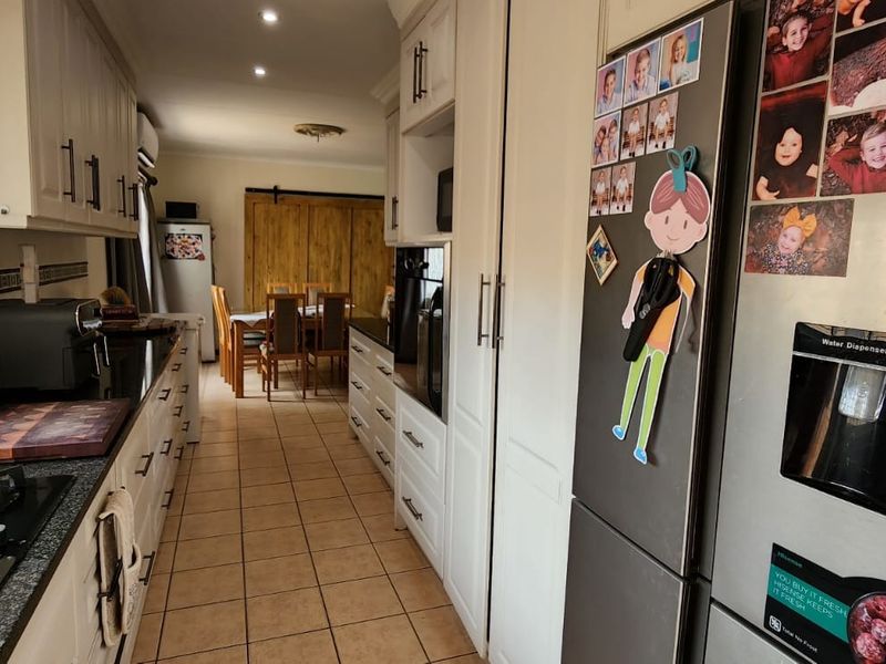 A functional kitchen featuring built-in cabinetry, granite countertops, and a gas hob, with an open-plan layout leading into the dining area.