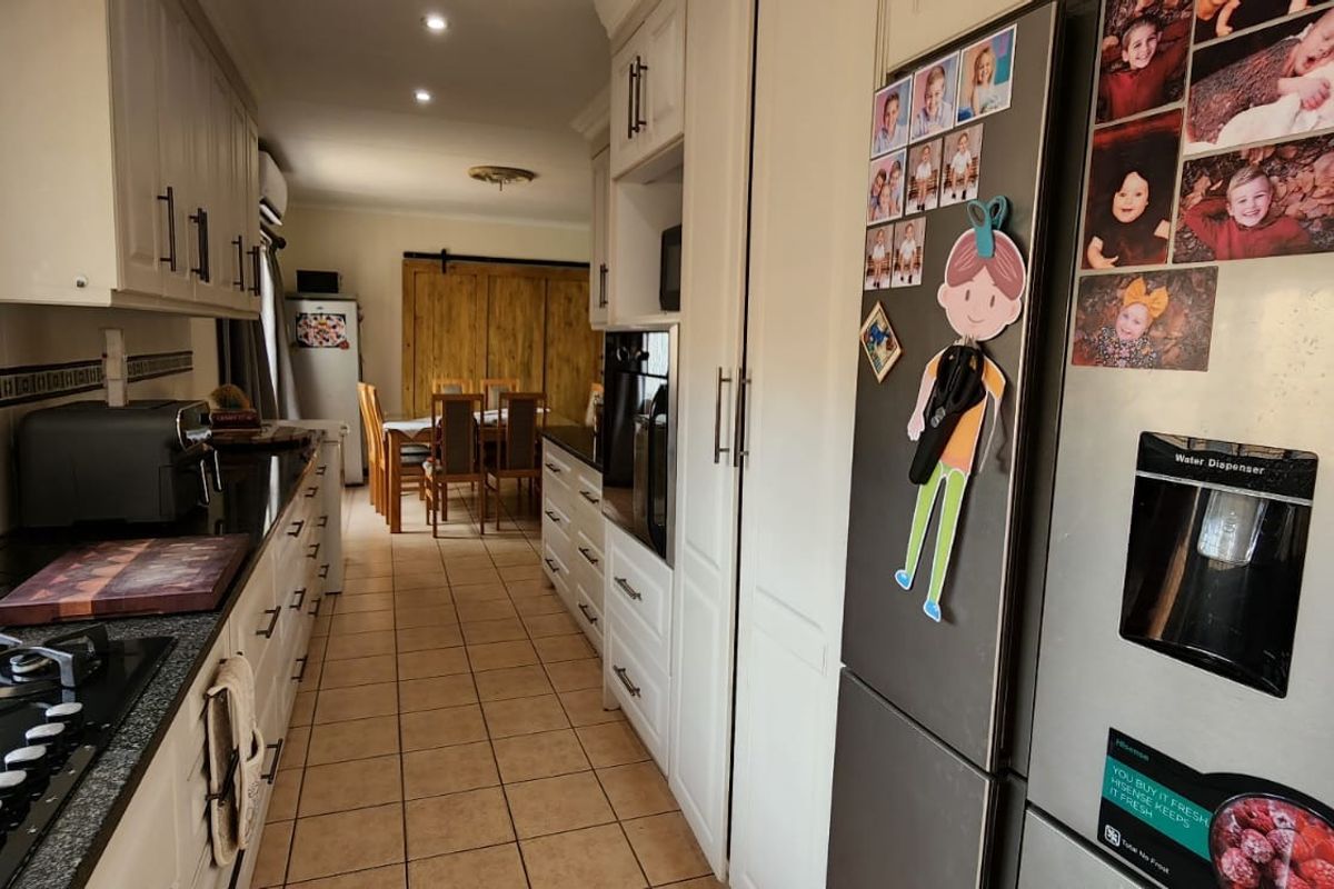 A functional kitchen featuring built-in cabinetry, granite countertops, and a gas hob, with an open-plan layout leading into the dining area.