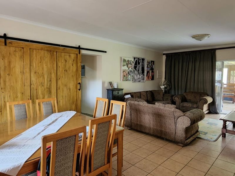Spacious open-plan living and dining area featuring tiled flooring, a distinctive wooden sliding barn door, and direct access to an outdoor patio space.
