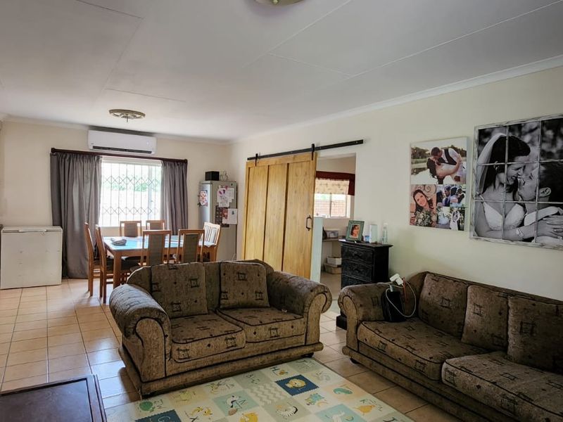 Spacious open-plan living and dining area featuring tiled flooring, an air conditioning unit, and a sliding barn door leading to an adjacent space.