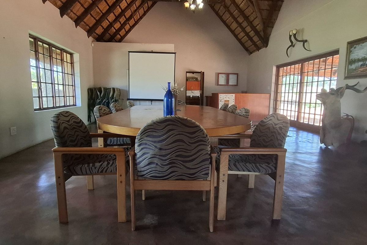 Spacious living area featuring a high thatched roof with exposed timber trusses, polished concrete floors, and large windows providing ample natural light.