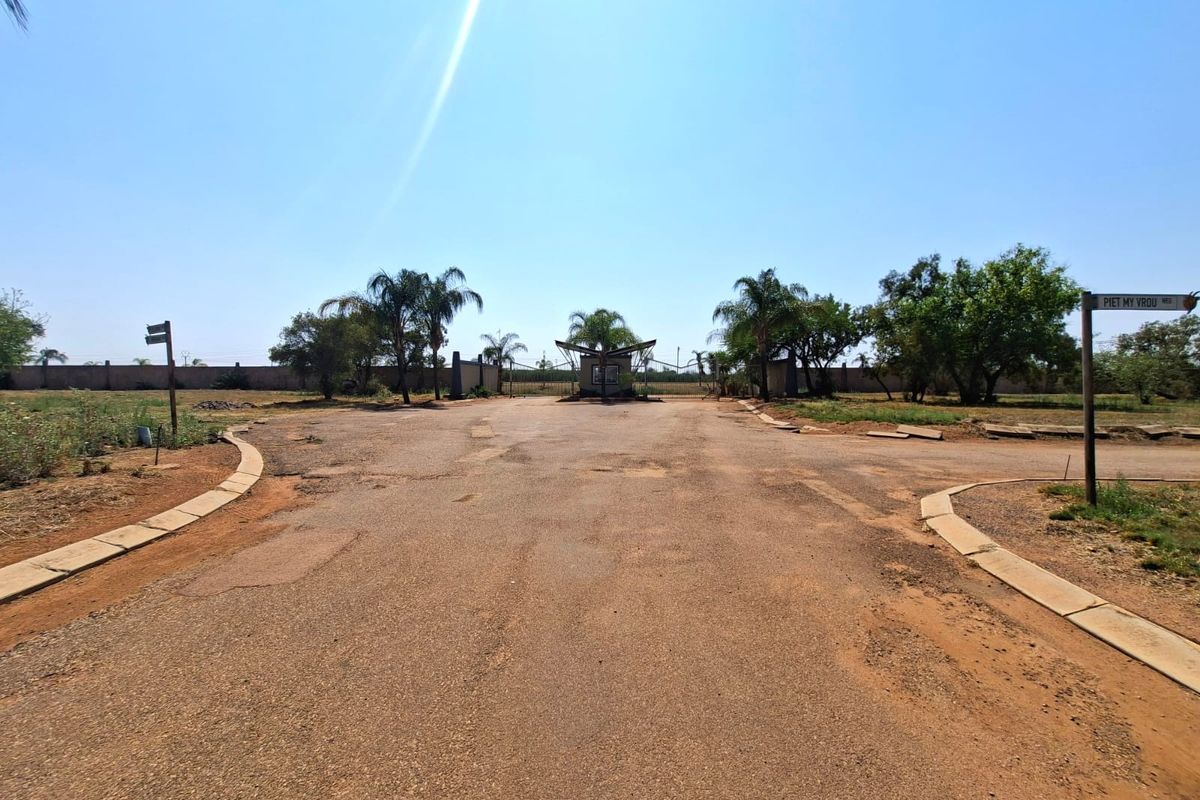View of the entrance to the residential property featuring an asphalt driveway, security gate, and perimeter wall.